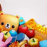 Leker og matvarer som inkluderer en bamse, en badeand, pommes frites, en jordbær, pizza, og en kanin mot en hvit bakgrunn