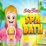 En tegneserie baby med lys oransje hår sitter i en rosa stol, med teksten Baby Hazel Spa Bath ved siden av seg, og to små scener med strand- og bademotiver i bakgrunnen