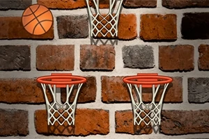 En bakgrunn av murstein med tre basketballkurver og en basketball i luften