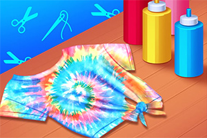 Fargerik tie-dye t-skjorte med spiraldesign ved siden av flasker med farge på et bord