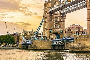 Tower Bridge i London over Themsen ved solnedgang, omgitt av historiske bygninger og en kran