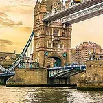 Tower Bridge i London over Themsen ved solnedgang, omgitt av historiske bygninger og en kran