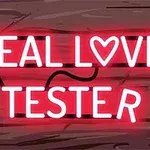 Neonlys i rødt med teksten REAL LOVE TESTER mot en bakgrunn av treplanker
