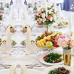 Elegant oppdekking med blomsterarrangementer, fruktfat og dekorative servietter på et langbord