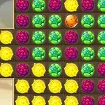 Fargerike frukter arrangert i et rutenett med lilla, grønne og gule bær samt en oransje frukt i midten