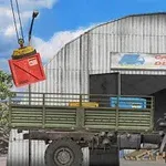 En lastebil står foran en lagerbygning med et skilt som sier Cargo Delivery, mens en kran løfter en rød container