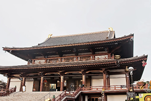 Tradisjonelt japansk tempel med store trebjelker og skråtak, omgitt av en trapp og besøkende
