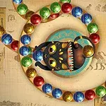 En svart kattfigur med fargerike perler rundt seg på en bakgrunn med egyptiske symboler